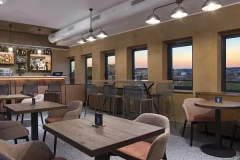 Bar del DoubleTree by Hilton Rome Monti con grandi finestre affacciate sulla città al tramonto