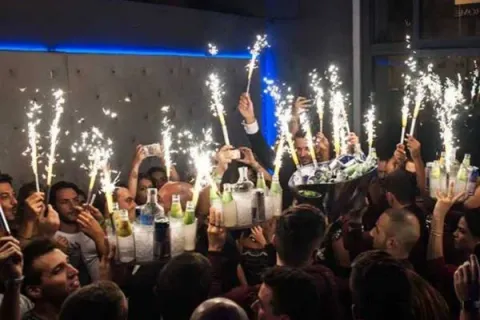 Bottiglie con sparkler servite ai tavoli della discoteca dell’Exe Roma