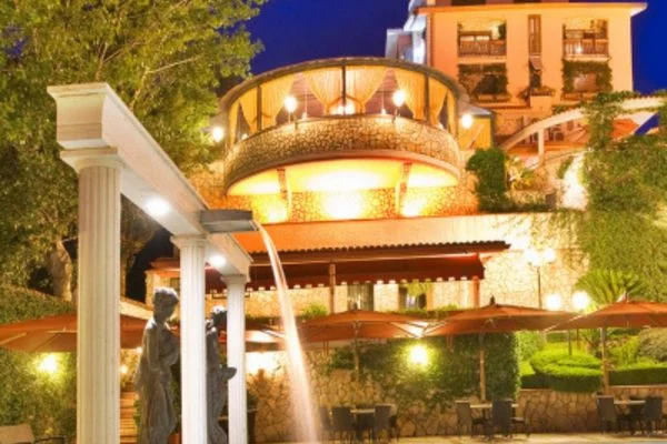Esterno illuminato della Residenza Castelverde a Roma con fontana e portico