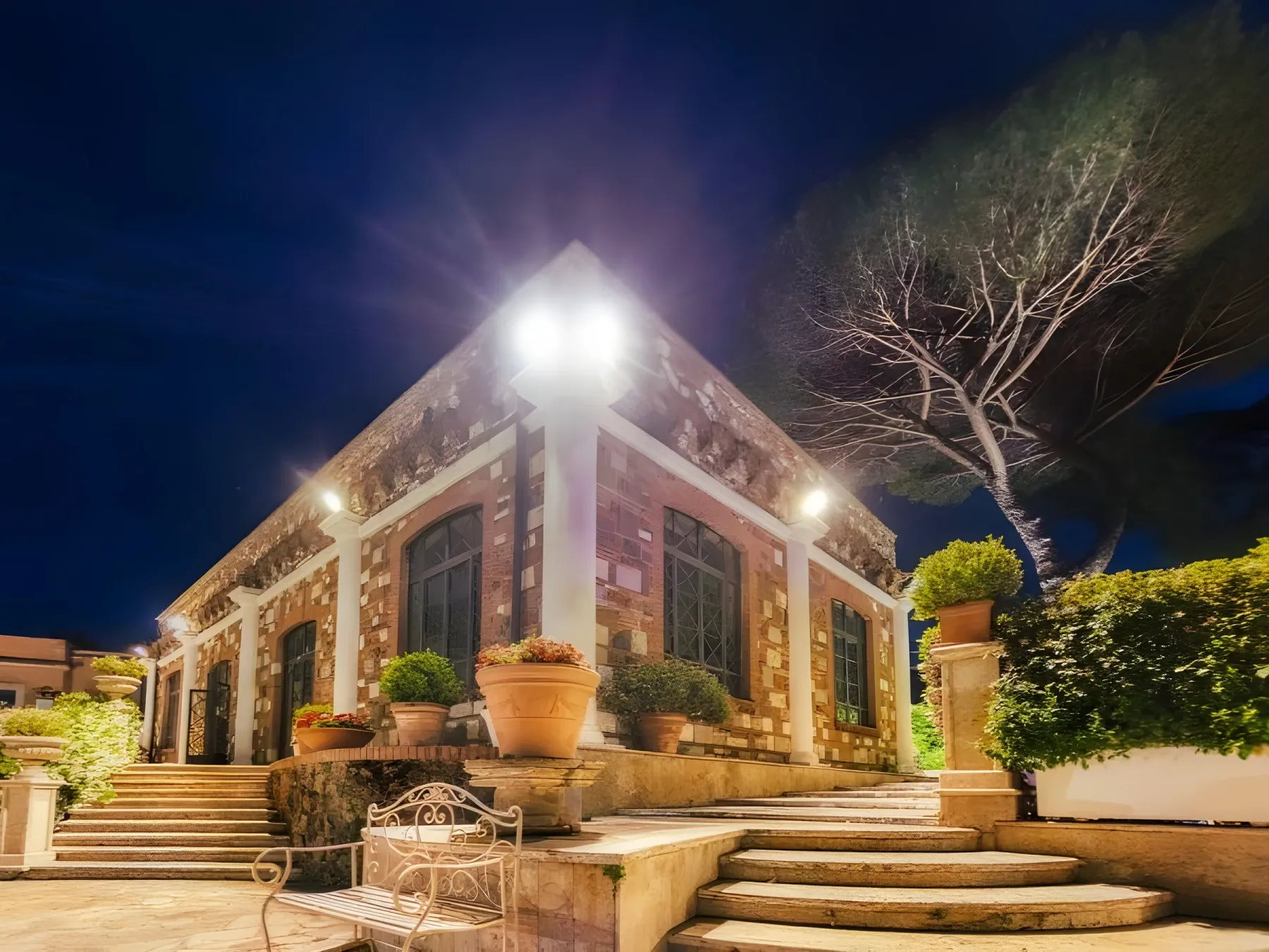 Facciata di Villa dei Cesari illuminata di sera, con la scalinata d’ingresso