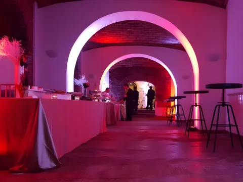 Sala di Villa dei Cesari con arco illuminato di rosa e banco del buffet